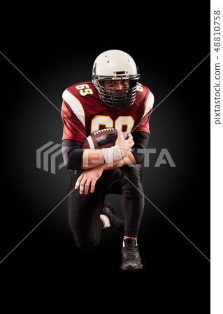 Portrait of American football player holding a ball with both his hands 48810758
