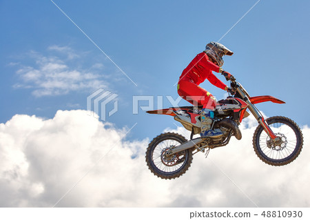 Extreme sports background - silhouette of biker jumping on motorbike on sunset, against the blue sky Extreme sports background - silhouette of biker jumping on motorbike on sunset, against the blue sky 48810930