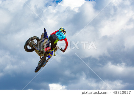Extreme sports background - silhouette of biker jumping on motorbike on sunset, against the blue sky 48810937