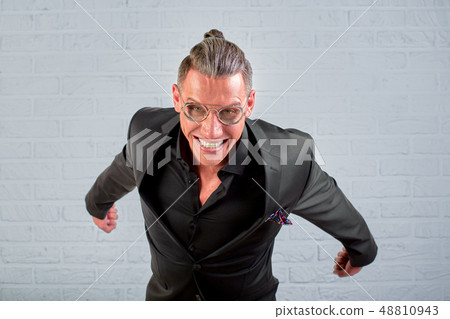 Close up portrait of a happy young businessman wearing glasses, dressed in a black suit, looks into 48810943