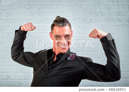 Close up portrait of a happy young businessman wearing glasses dressed in a black suit shows hands 48810951