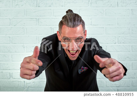 Close up portrait of a happy young businessman wearing glasses dressed in a black suit shows hands 48810955