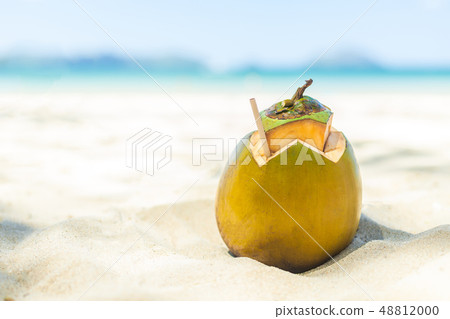 Fresh young coconut lying on the sand beach background with straw ready for drink. 48812000
