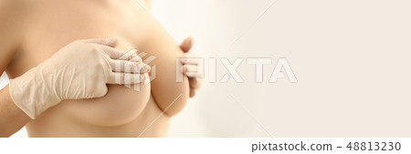 Female hand in gloves holding breast closeup 48813230