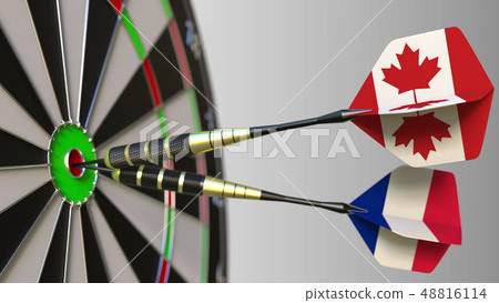Flags of Canada and France on darts hitting bullseye of the target. International cooperation or Flags of Canada and France on darts hitting bullseye of the target. International cooperation or 48816114