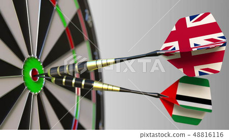 Flags of the United Kingdom and the UAE on darts hitting bullseye of the target. International Flags of the United Kingdom and the UAE on darts hitting bullseye of the target. International 48816116