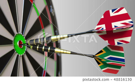 Flags of the United Kingdom and South Africa on darts hitting bullseye of the target. International 48816130