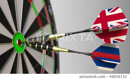 Flags of the United Kingdom and Russia on darts hitting bullseye of the target. International 48816132