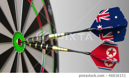 Flags of Australia and North Korea on darts hitting bullseye of the target. International 48816151