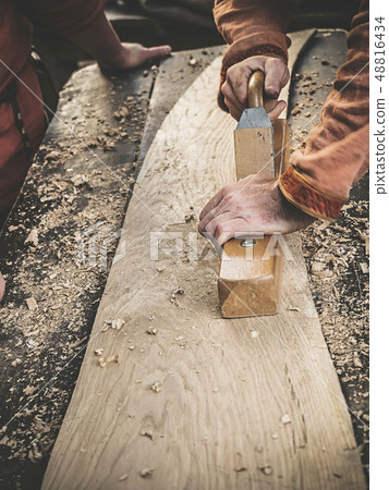 Carpenter in Medieval Cotton Clothes Working With a Wood by Plane. Man Manually Hews a Wooden Board 48816434