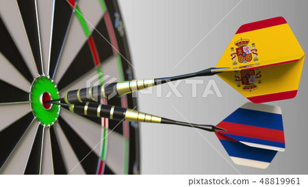 Flags of Spain and Russia on darts hitting bullseye of the target. International cooperation or 48819961