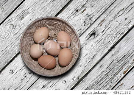 eggs in a basketl on old wooden board 48821152