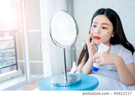 Asian teenage woman looking at mirror and squeeze Asian teenage woman looking at mirror and squeeze 48822517