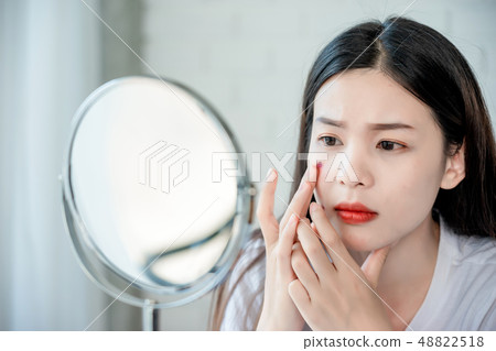 Asian teenage woman looking at mirror and squeeze Asian teenage woman looking at mirror and squeeze 48822518