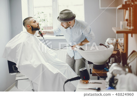 The man cuts his beard in the barbershop. The man cuts his beard in the barbershop. 48824960