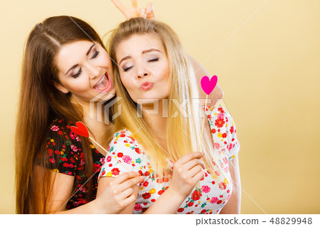 Two happy women holding heart on stick Two happy women holding heart on stick 48829948