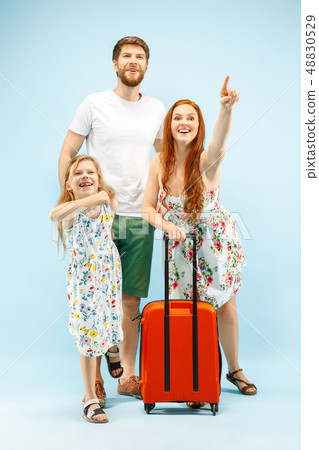 Happy parent with daughter and suitcase at studio isolated on blue background Happy parent with daughter and suitcase at studio isolated on blue background 48830529