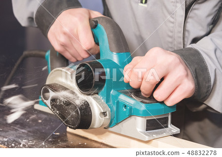 The hands of a carpenter working woodworking power tools. Close up of the work of the electric 48832278
