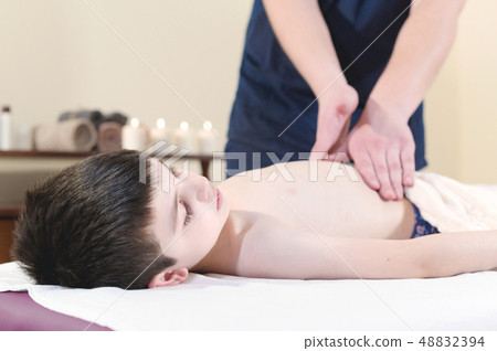 A little boy at the reception at a professional masseuse. Male manual worker gives massage to the 48832394