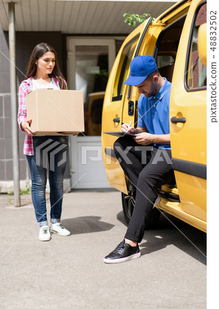 Delivery man fills documents sitting in the trunk 48832502