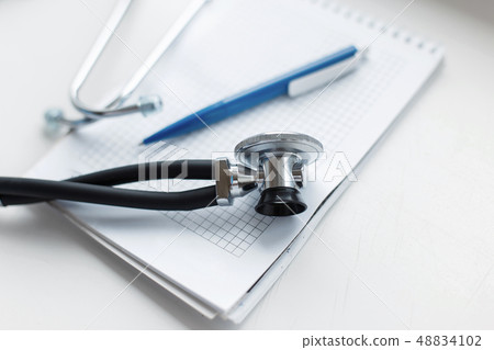 Phonendoscope with a pen and a notebook on a white 48834102
