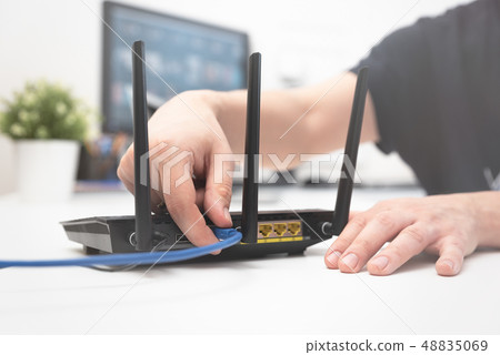 Man connects the internet cable to the router Man connects the internet cable to the router 48835069