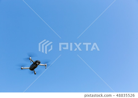 A drone flying against the blue sky A drone flying against the blue sky 48835526