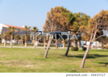 A drone with digital camera flying in the park A drone with digital camera flying in the park 48835527