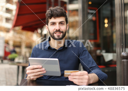 Young father buying online with card by smartphone at cafe in . Young father buying online with card by smartphone at cafe in . 48836575