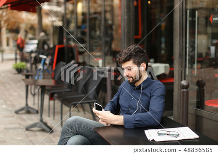 American boy listening to music at cafe with earphones and smart 48836585