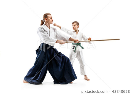 Man and teen boy fighting with wooden swords at Aikido training in martial arts school Man and teen boy fighting with wooden swords at Aikido training in martial arts school 48840638