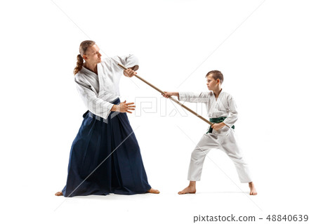 Man and teen boy fighting with wooden swords at Aikido training in martial arts school Man and teen boy fighting with wooden swords at Aikido training in martial arts school 48840639