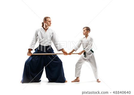 Man and teen boy fighting with wooden swords at Aikido training in martial arts school 48840640