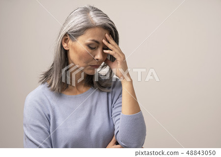 Mature Asian woman touches her forehead in distress Mature Asian woman touches her forehead in distress 48843050