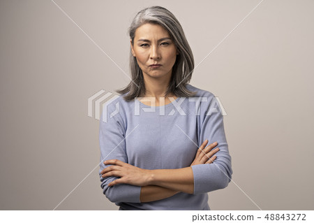 Serious Mongolian Woman with Gray Hair Against the Backdrop of Gray. Serious Mongolian Woman with Gray Hair Against the Backdrop of Gray. 48843272