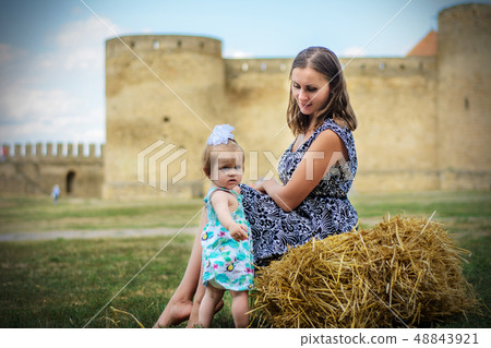 A young mother with her daughter sits on a straw A young mother with her daughter sits on a straw 48843921