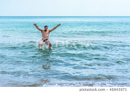 A sports man jumping over the sea waves in the 48843971