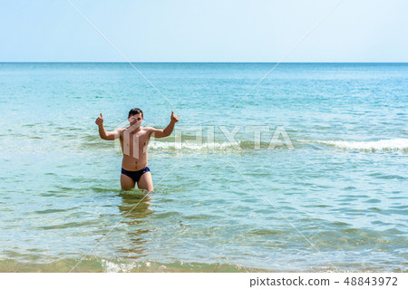 A sports man shows a sign ok in the waves of the 48843972