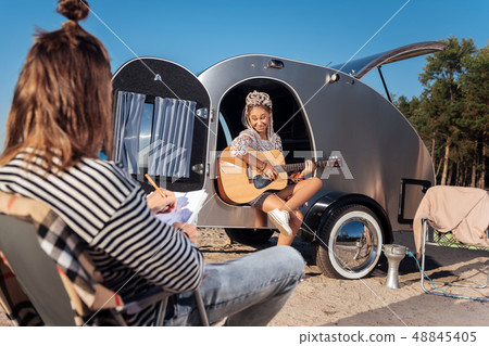 Woman wearing white sneakers feeling joyful playing the guitar Woman wearing white sneakers feeling joyful playing the guitar 48845405