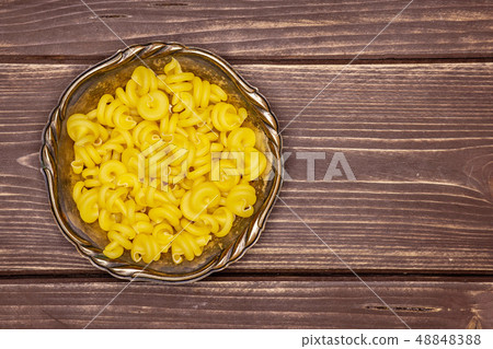 Raw pasta funghetto on brown wood Raw pasta funghetto on brown wood 48848388