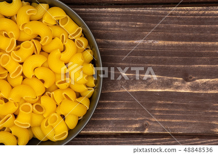 Raw pasta pipe rigate on brown wood 48848536