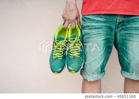 Man holding sport shoes in his hand. 48851168