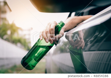 Asian man holding a bottle of beer outside the car 48854166