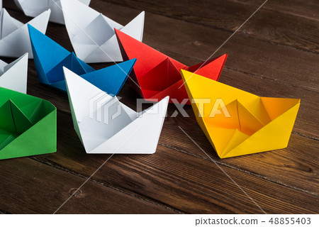 Business leadership concept with white and color paper boats on wooden table Business leadership concept with white and color paper boats on wooden table 48855403