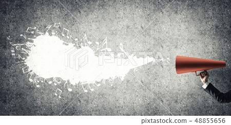 Hand of businesswoman holding red paper trumpet against concrete background 48855656