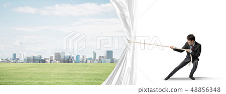 Young man opening white curtain and presenting modern city landscape 48856348