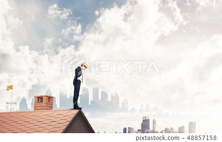 Engineer man standing on roof and looking down. Mixed media Engineer man standing on roof and looking down. Mixed media 48857158