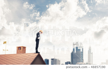 Engineer man standing on roof and looking down. Mixed media Engineer man standing on roof and looking down. Mixed media 48857190