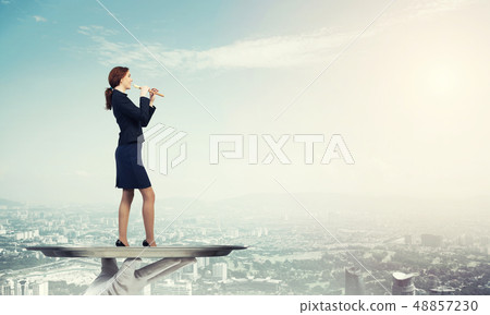 Attractive businesswoman on metal tray playing fife against cityscape background Attractive businesswoman on metal tray playing fife against cityscape background 48857230