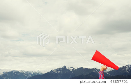Hand of woman holding paper trumpet against natural landscape background Hand of woman holding paper trumpet against natural landscape background 48857701